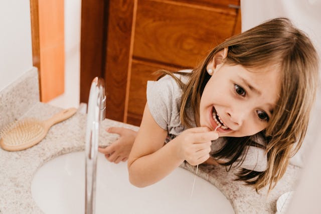 child flossing her teeth