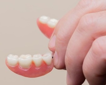 denture (1) hand holding a seniors denture